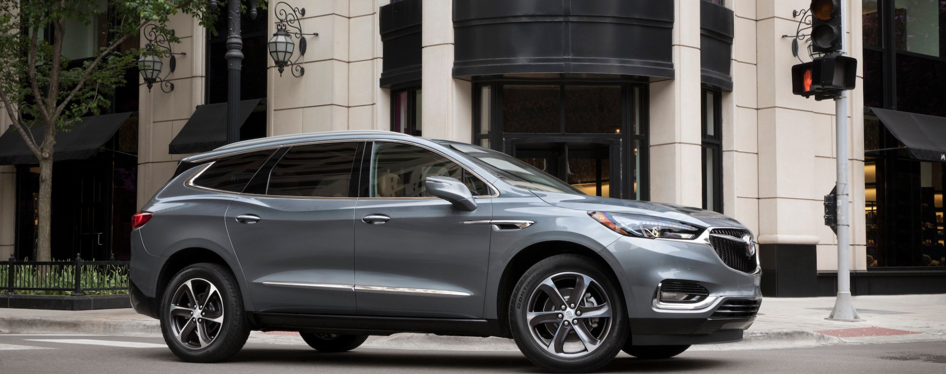 A dark-silver 2021 Buick Enclave midsize three-row SUV at a city intersection