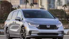 A silver 2021 Honda Odyssey parked outside with a city background
