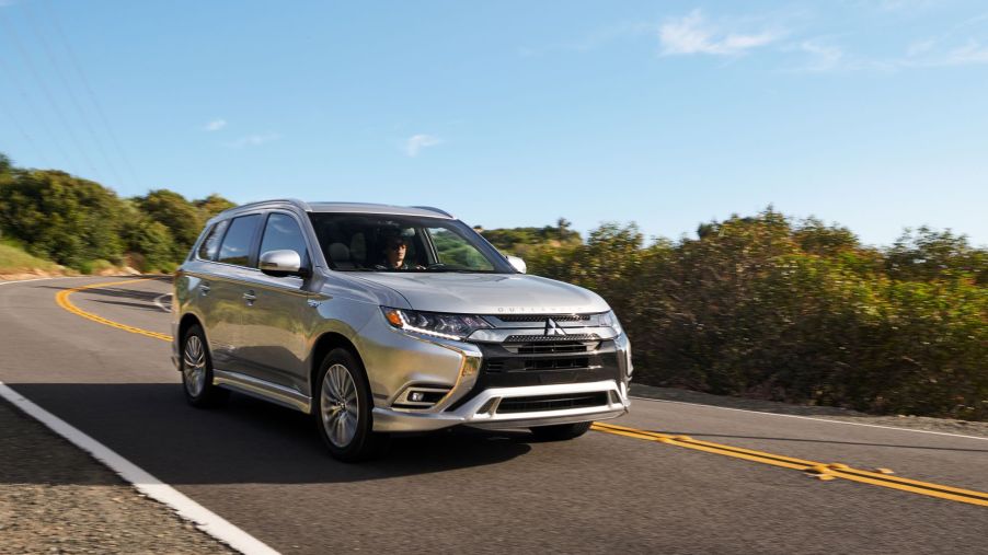 A 2021 Mitsubishi Outlander PHEV model in silver gray driving down a strip of highway