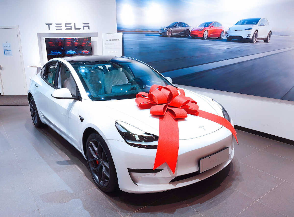 A white 2021 Tesla Model 3 with a big red bow on its hood at a Tesla store in Shanghai in June 2021