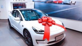 A white 2021 Tesla Model 3 with a big red bow on its hood at a Tesla store in Shanghai in June 2021