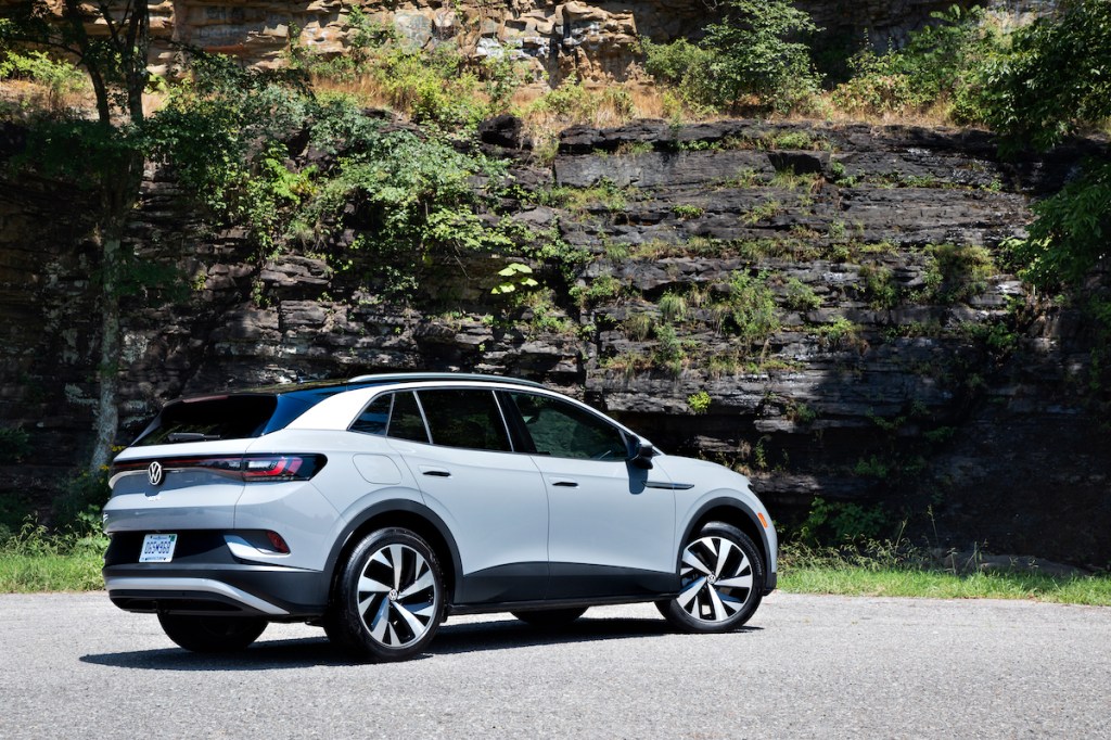 A light-gray 2021 Volkswagen ID.4 electric crossover SUV parked on a road next to a rocky cliff