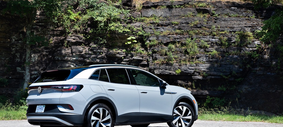 A light-gray 2021 Volkswagen ID.4 electric crossover SUV parked on a road next to a rocky cliff