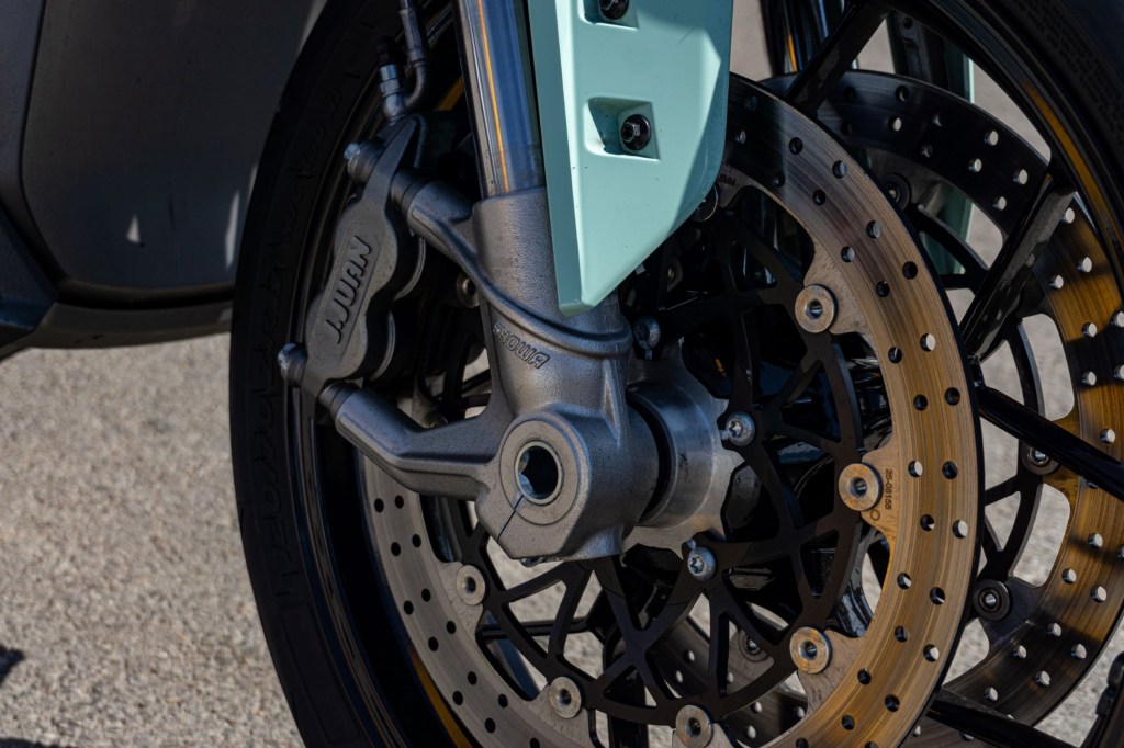 A close-up view of a mint-green 2021 Zero SR/F Premium's front brakes and the lower half of its fork