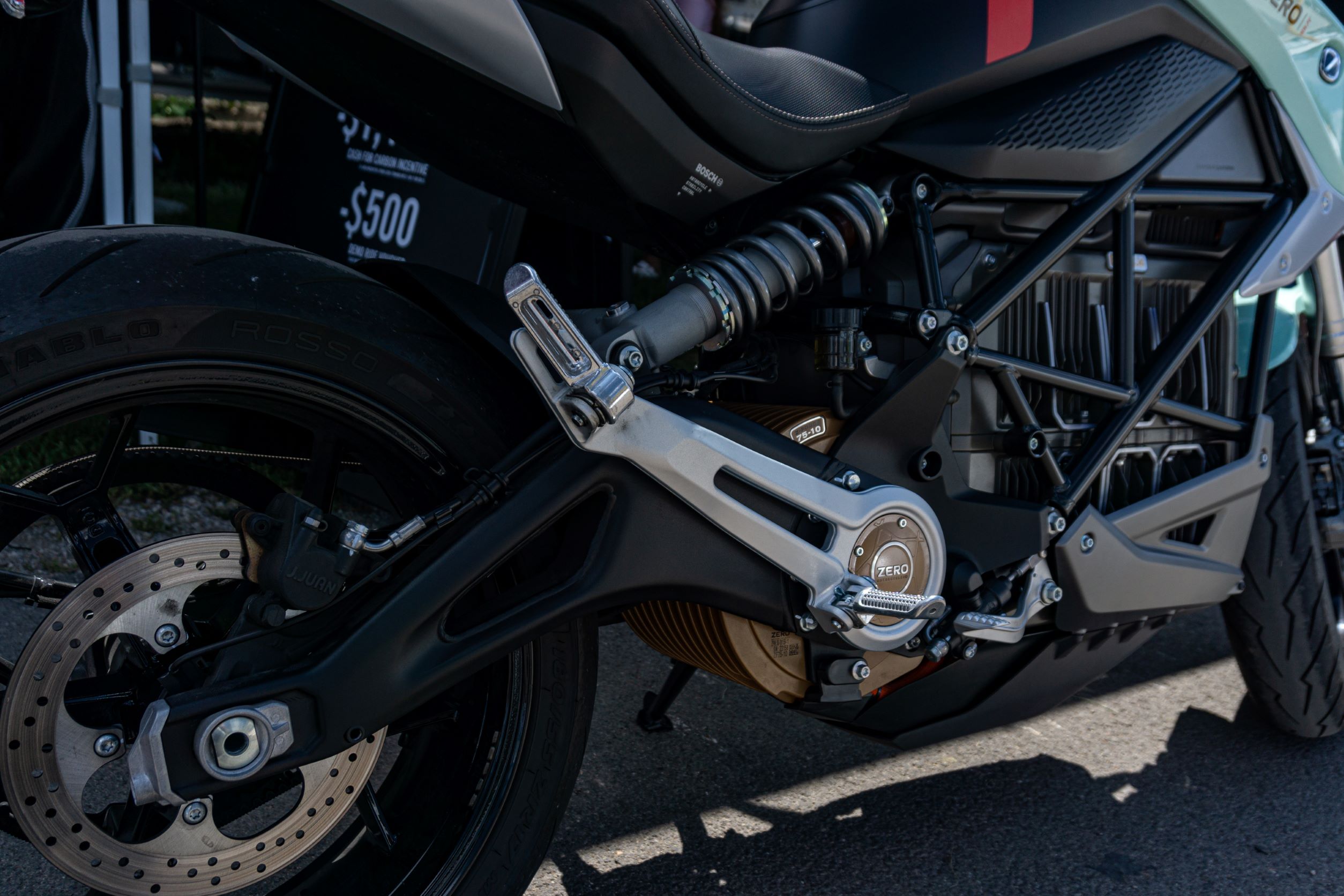 The rear 3/4 view of a mint-green 2021 Zero SR/F Premium's rear wheel, suspension, and electric drivetrain