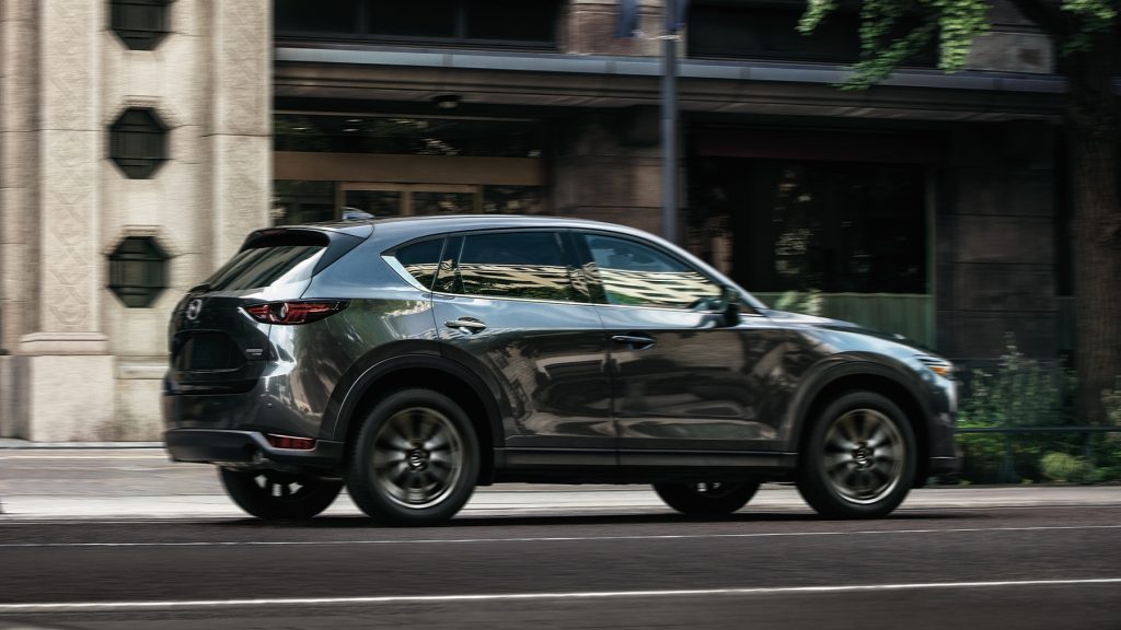 A gray 2021 Mazda CX-5 driving through a city.