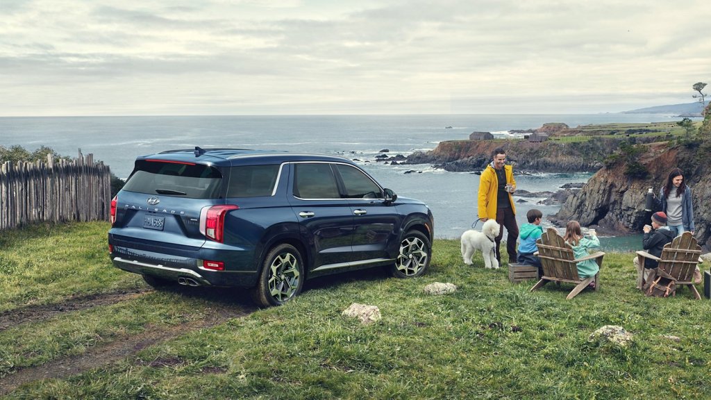 A navy blue 2021 Hyundai Palisade parked at the edge of a cliff iwth a family enjoying hot cocoa.
