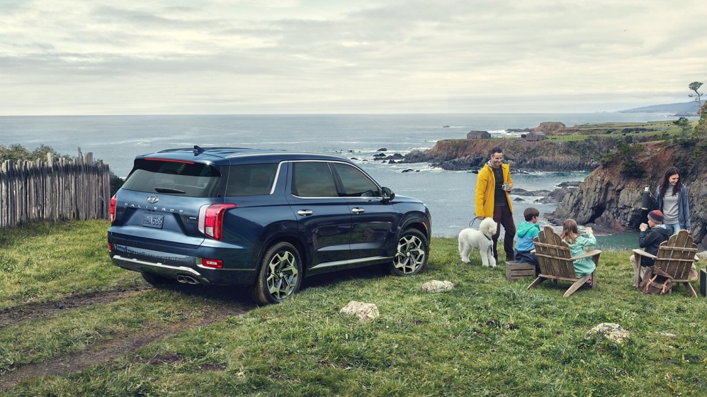 A navy blue 2021 Hyundai Palisade parked at the edge of a cliff iwth a family enjoying hot cocoa.