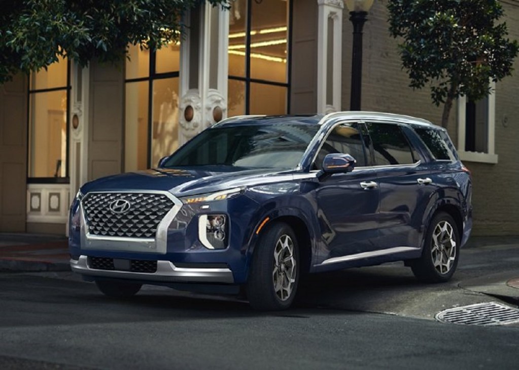A dark blue 2021 Hyundai Palisade pulling out of a side street.