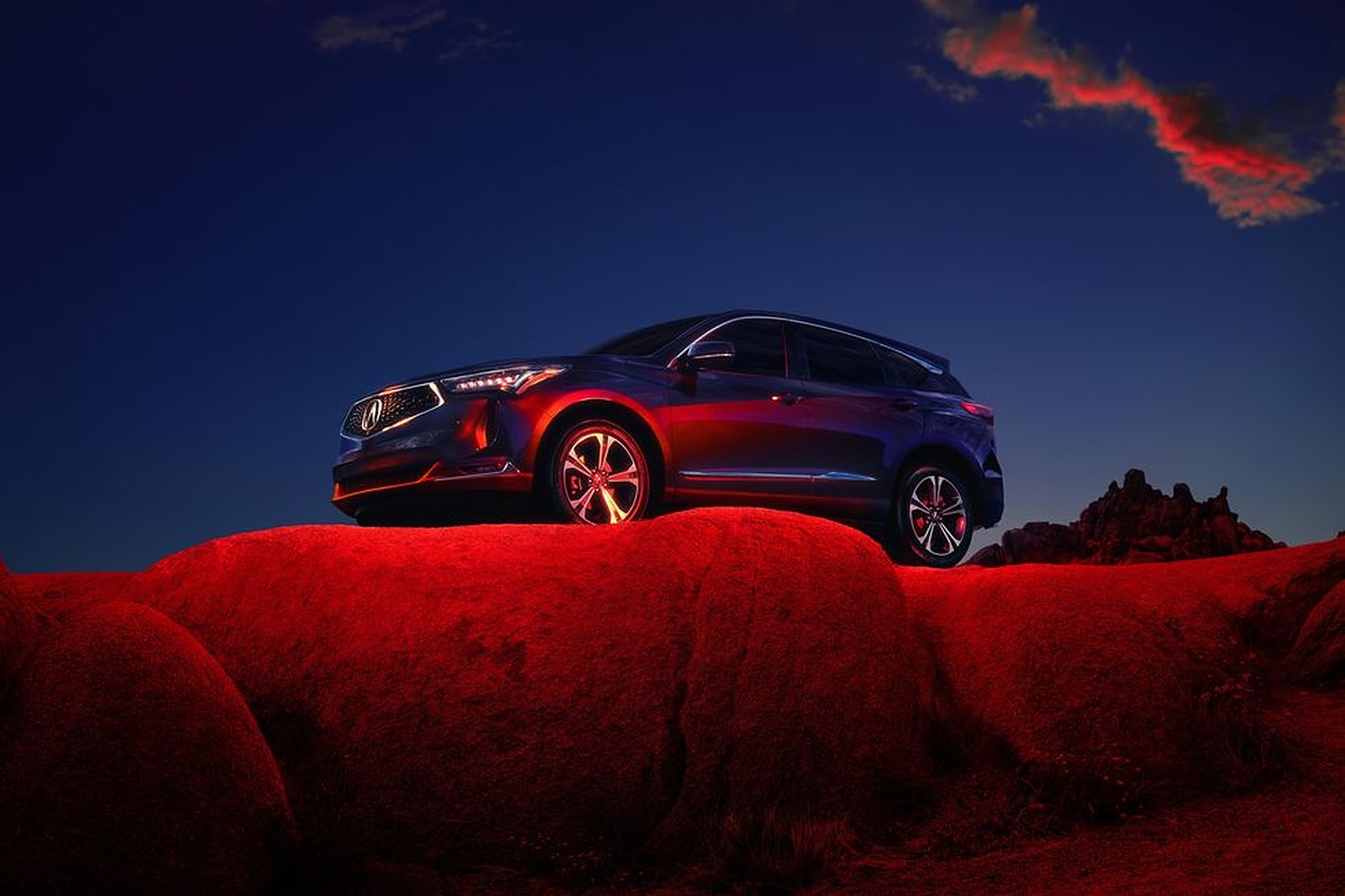 A blue 2022 Acura RDX parked outside on a cliff with red lighting
