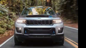 A silver 2022 Jeep Grand Cherokee 4xe driving down a wooded road.