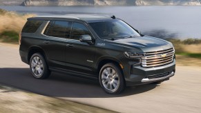 black 2022 Chevrolet Tahoe High Country driving near a lake