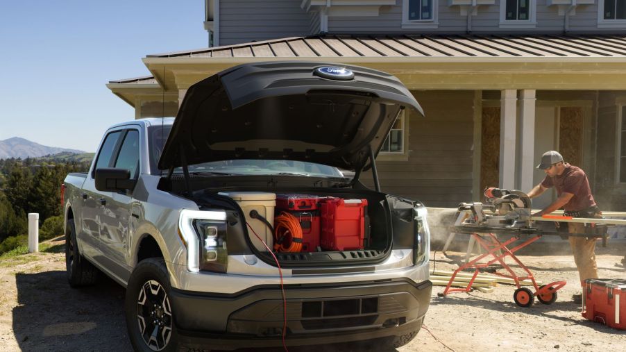 The front of a 2022 Ford F-150 Lightning with the frunk open at a construction site during a house build.
