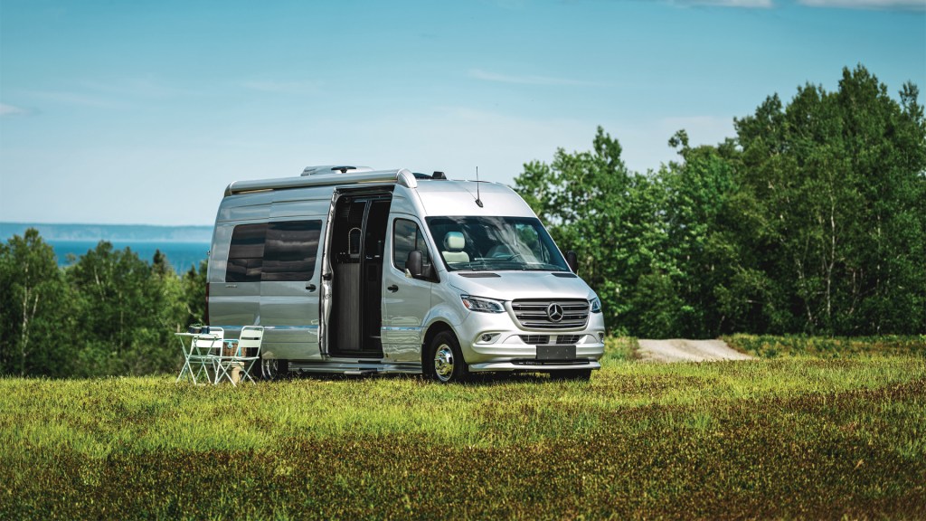 Airstream 24GL is parked in a lovely field with a table and chair set up. This is one of the best small RVs for couples