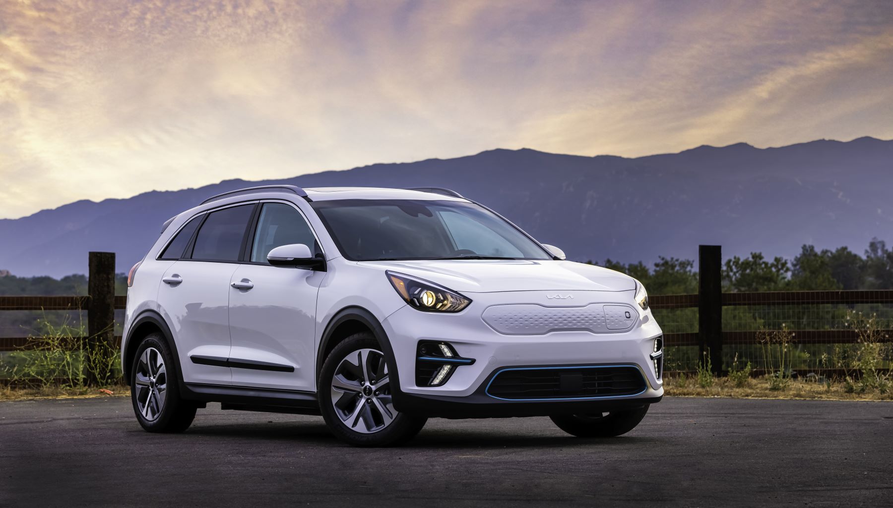 2022 Kia Niro EV in whit paint color parked by a barb wire wooden fence at sunset
