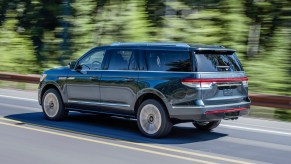 A dark-blue 2022 Lincoln Navigator SUV traveling on a highway past a blur of trees