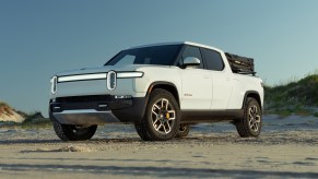 A white 2022 Rivian R1T parked in the sand on a beach