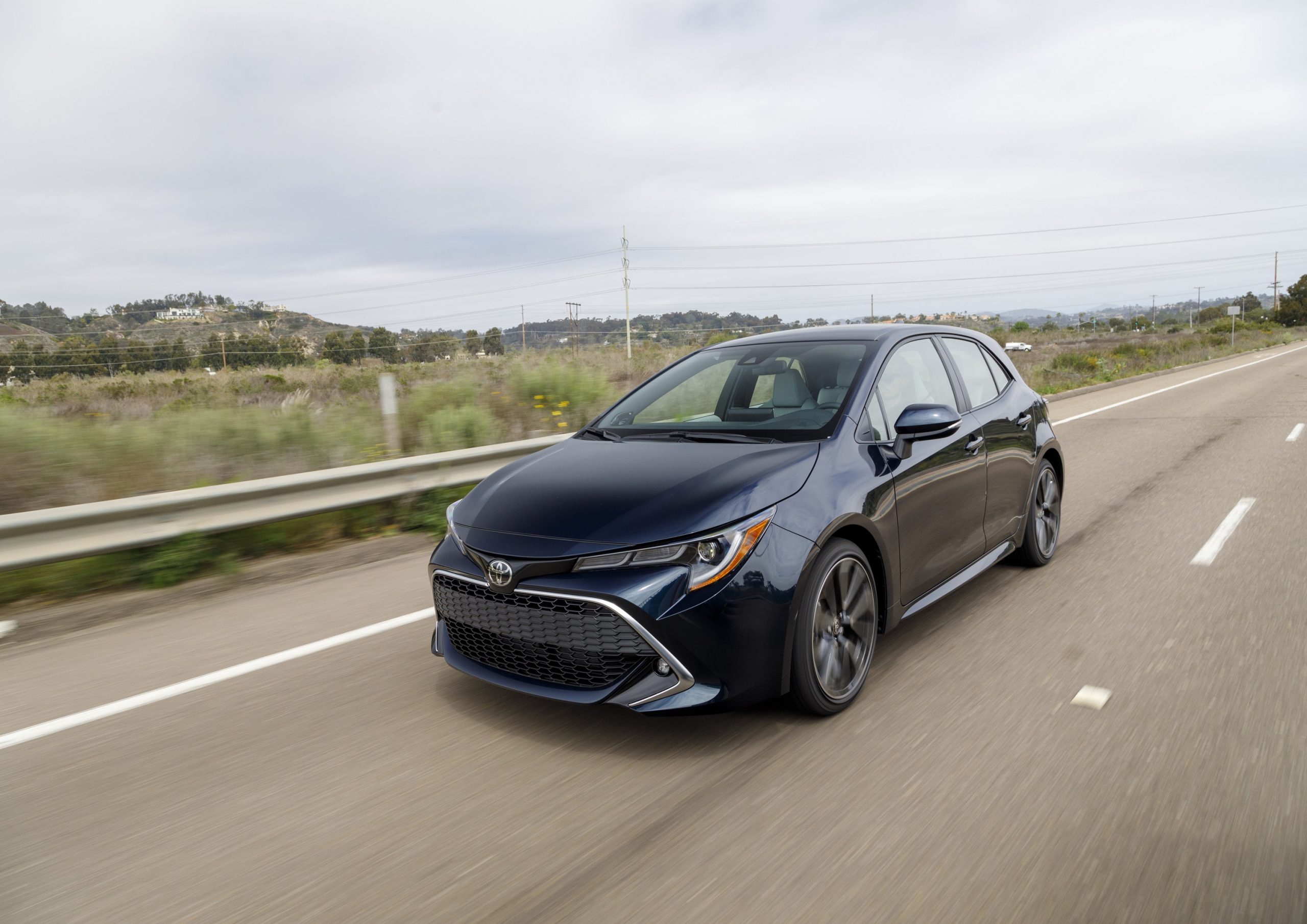 A blue 2022 Toyota Corolla hatchback shot from the front 3/4 while in motion