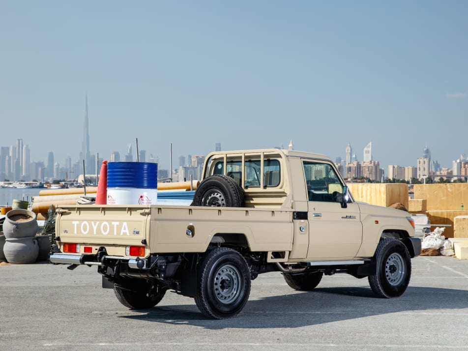 A tan 2022 Toyota LC70 pickup with cargo in the back parked outside