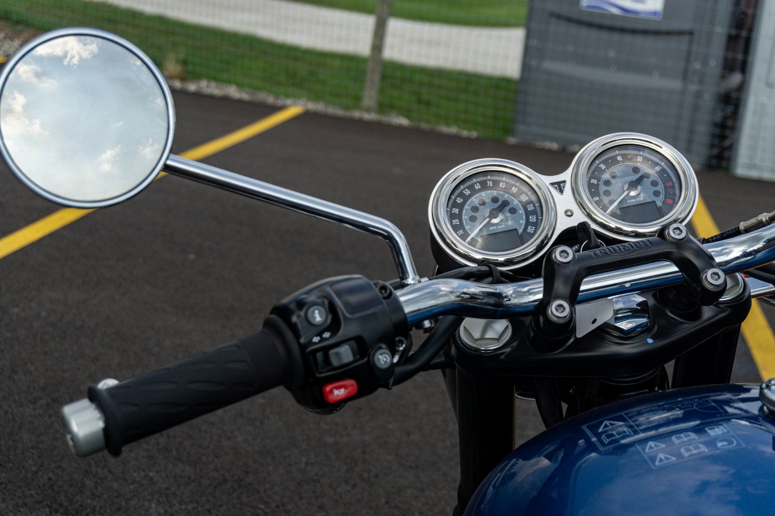 A close-up view of a blue-and-silver 2022 Triumph Bonneville T120's silver gauges