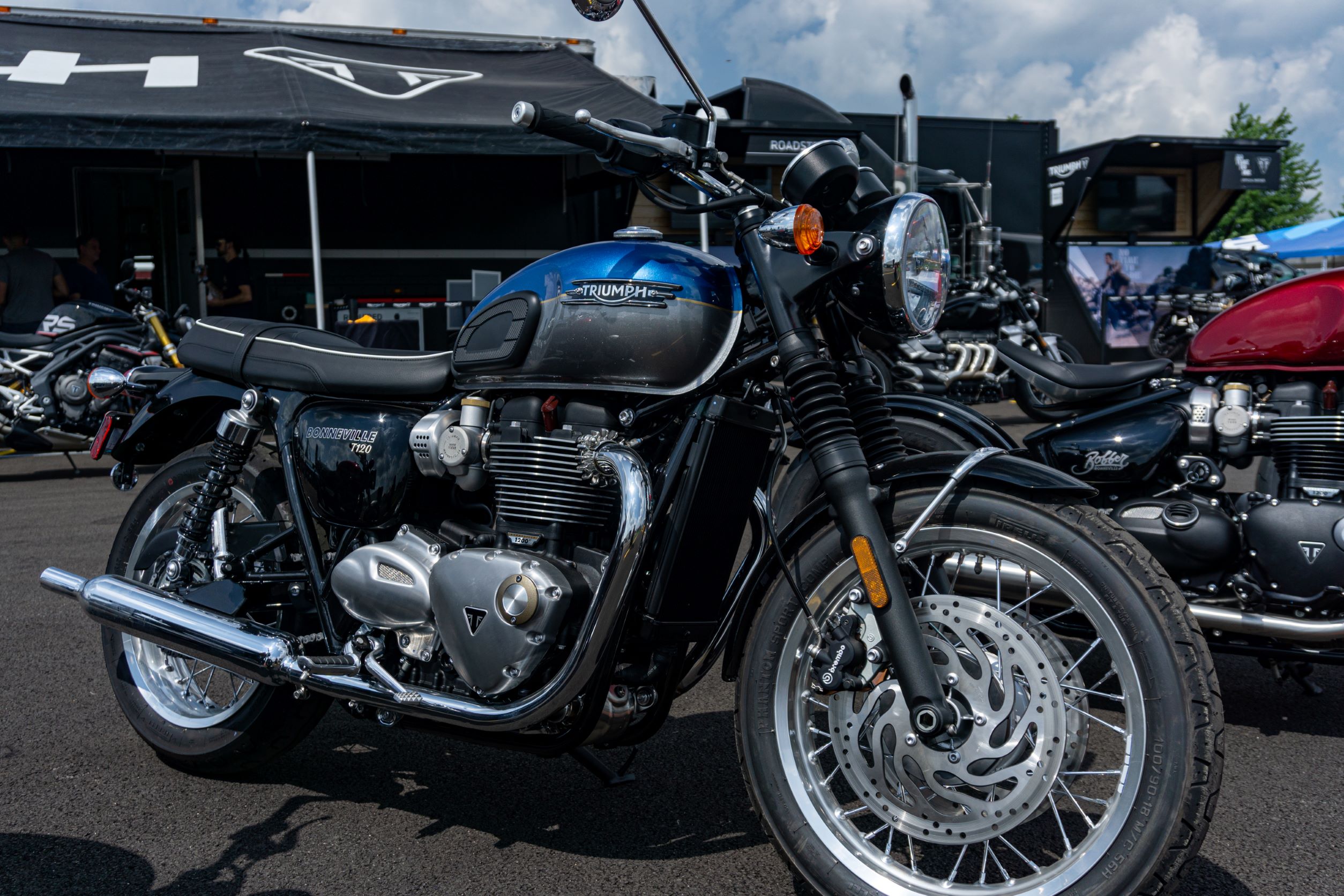 The side 3/4 view of a blue-and-silver 2022 Triumph Bonneville T120 in a parking lot