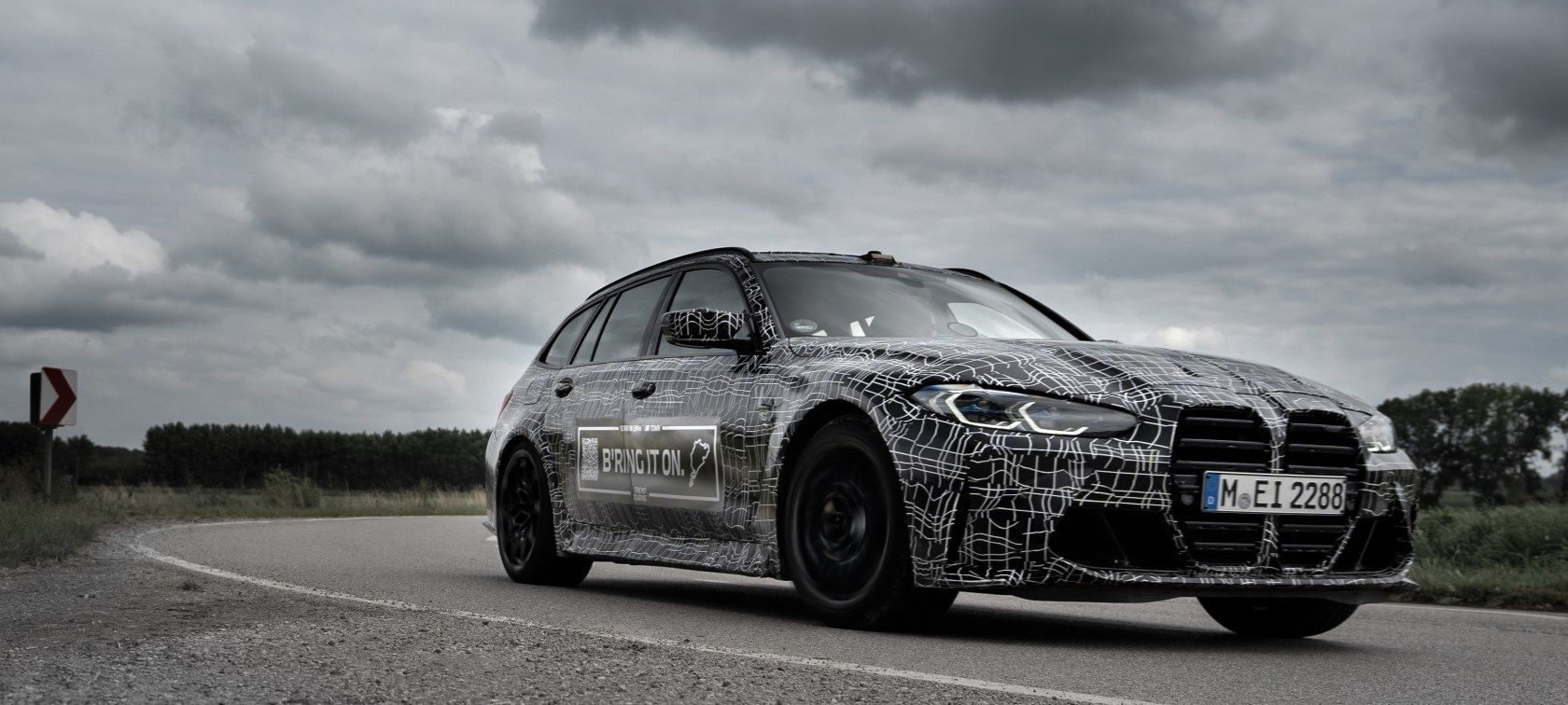 A BMW M3 Touring shows off the new BMW Kidney Grille while wrapped in camo, shot from the front 3/4
