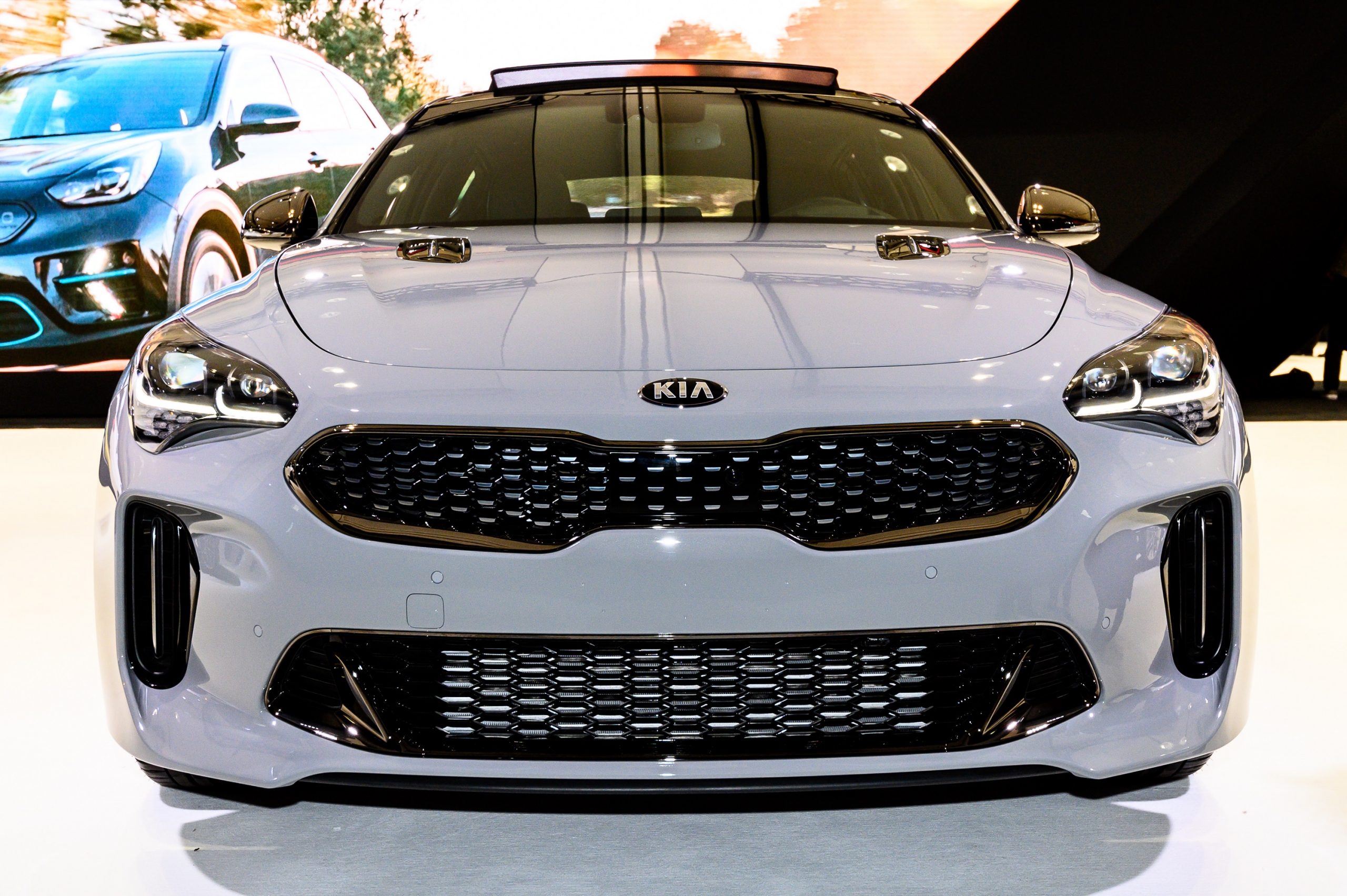 The 2022 Kia Stinger GT, shot from the front at an auto show in a pale grey paint