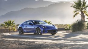 A blue Subaru BRZ among the palm trees in the desert