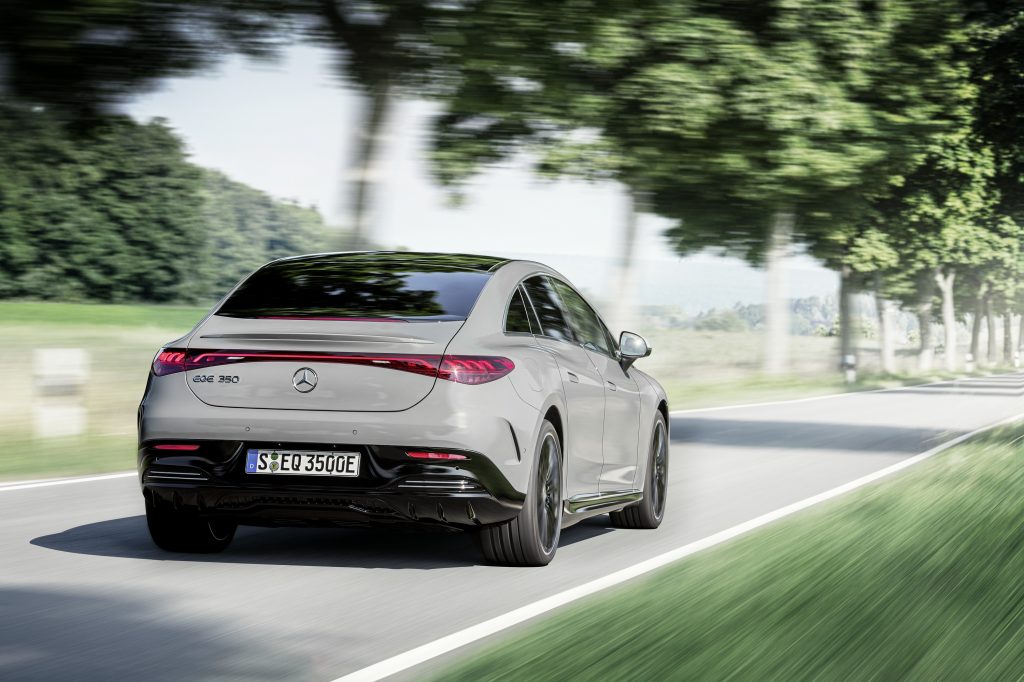 A steel-grey 2023 Mercedes-Benz EQE blasts down a shady back road