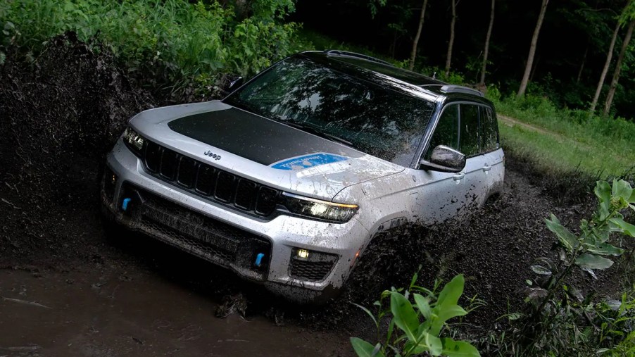 A white 2022 Jeep Grand Cherokee 4xe splashing through the mud.