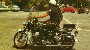 A Los Angeles police officer on a black-and-white Moto Guzzi Eldorado 850 police bike in a 1970s parking lot