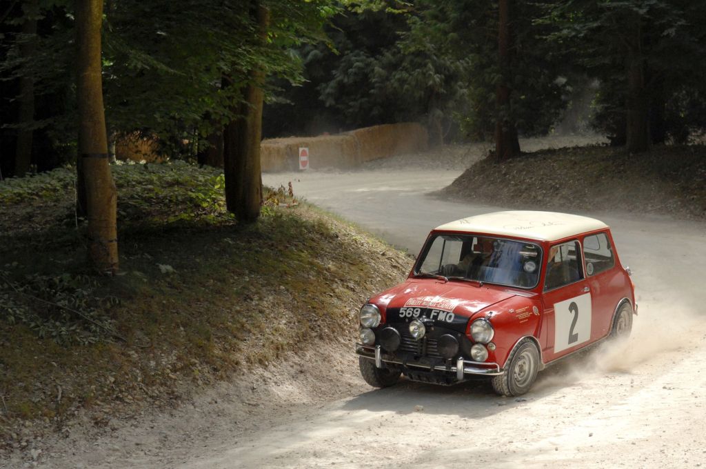 A classic red-and-white Austin Mini Cooper S drives around the 2009 Goodwood Festival of Speed Forest Rally Stage