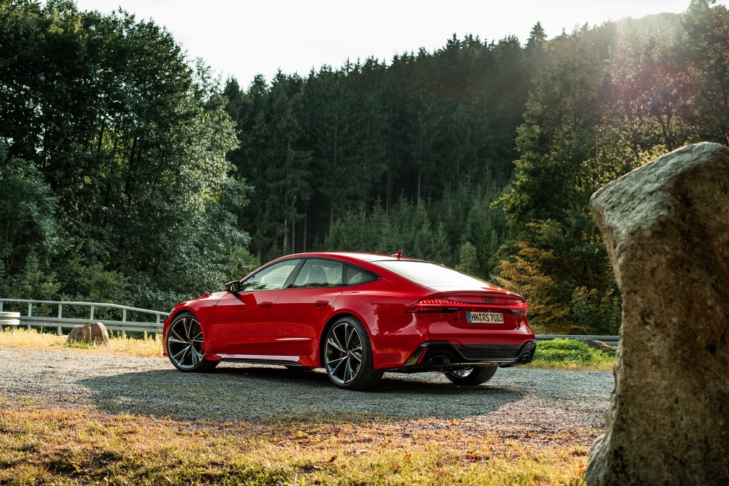 A red 2021 Audi RS7 luxury car shot in a forest from the rear 3/4 angle