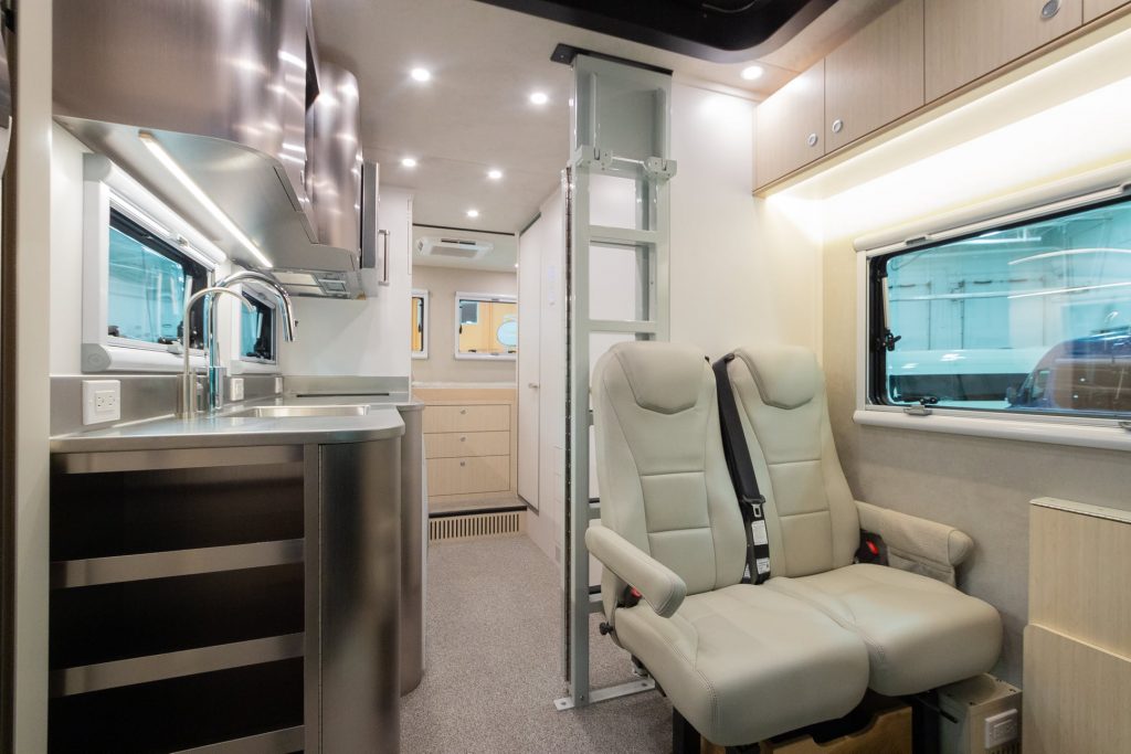 The leather seats, kitchen, and upper bed area ladder in the rear of the Advanced RV B Box 'Asteroid of Happiness'