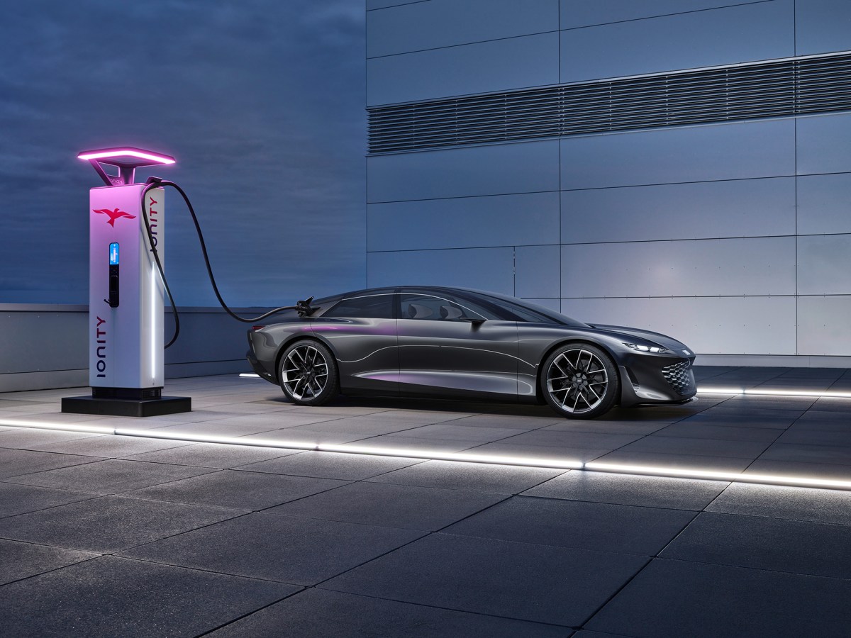 The Audi grandsphere concept at an EV charging station lit with pink led light at dusk.