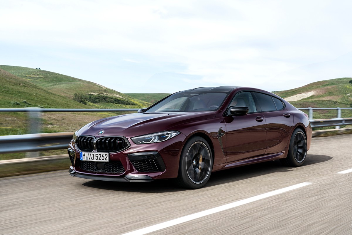 A dark purple BMW M850i x Grand Coupe driving down a road. This vehicle will serve as the canvas for the next BMW Art Car