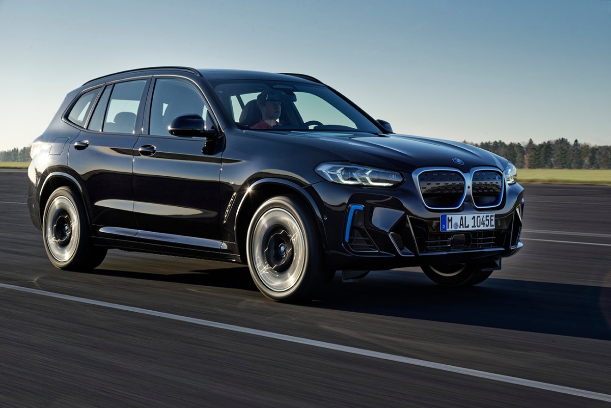 The new BMW iX3 EV crossover seen here in black with blue accents on the front bumper, and front grille.