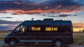 Camper Van Parked In Front Of Sunset