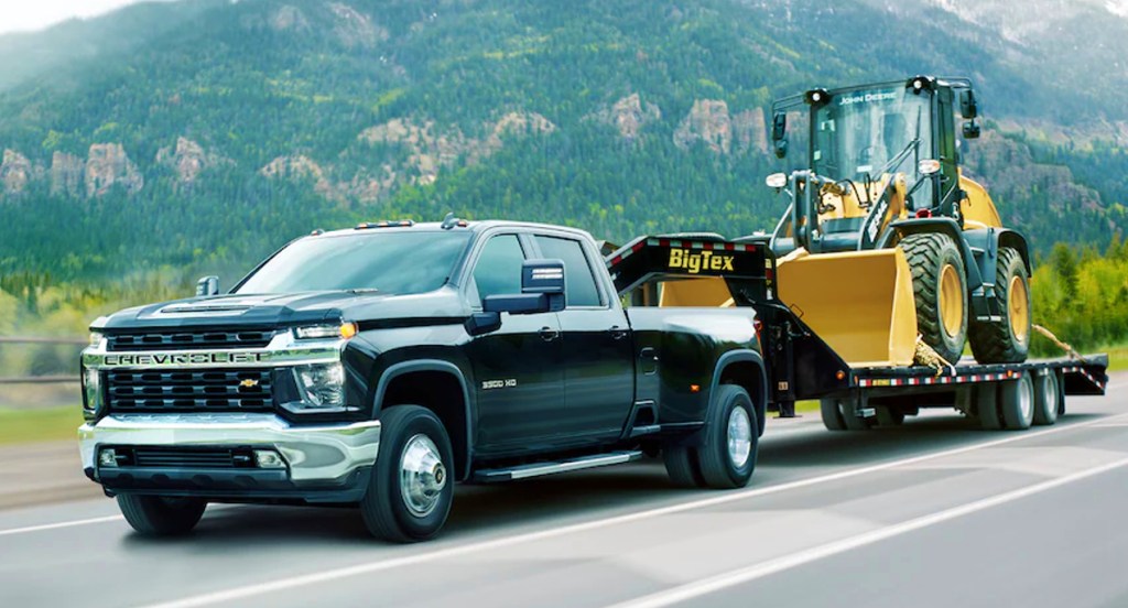 A black 2021 Chevrolet Silverado 3500 heavy duty pickup truck is towing a bulldozer.