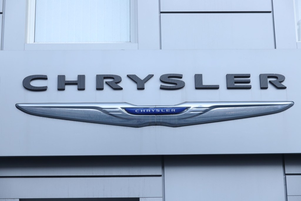 Silver, blue, and black Chrysler logo, maker of the Chrysler 300, on a white building.