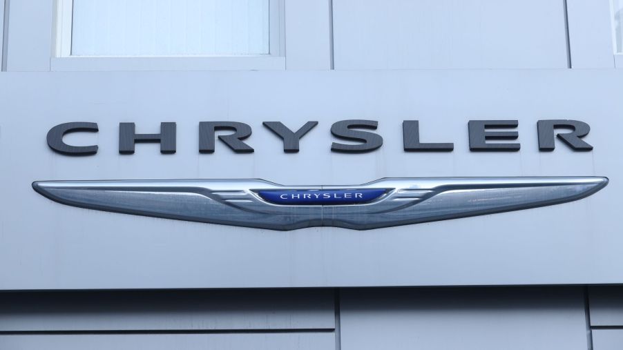 Silver, blue, and black Chrysler logo, maker of the Chrysler 300, on a white building.