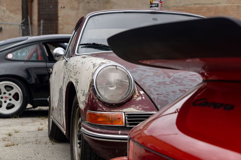 Classic early Porsche 911 with patina behind a red 1987 911 Carrera 3.2