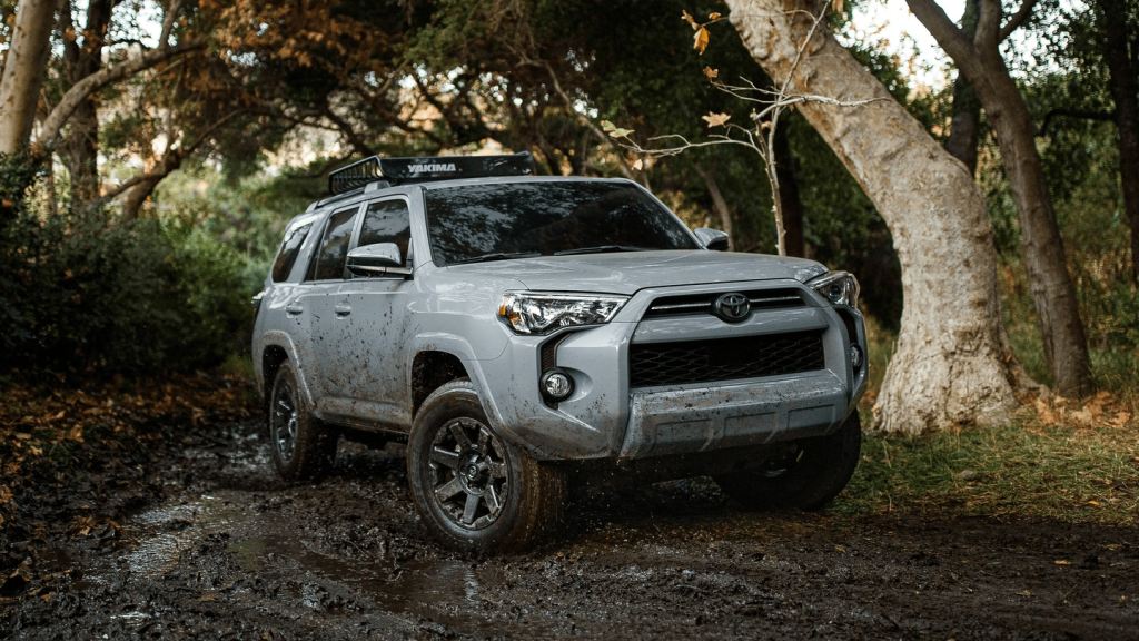 A white 2021 Toyota 4Runner drives through the woods.