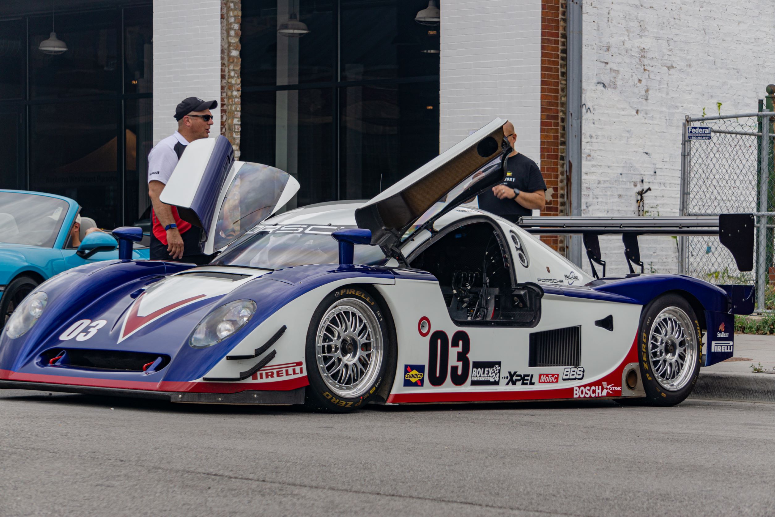 The front 3/4 view of Fall-Line Motorsports' white-blue-and-red Porsche Crawford Daytona Prototype with its left-side door open