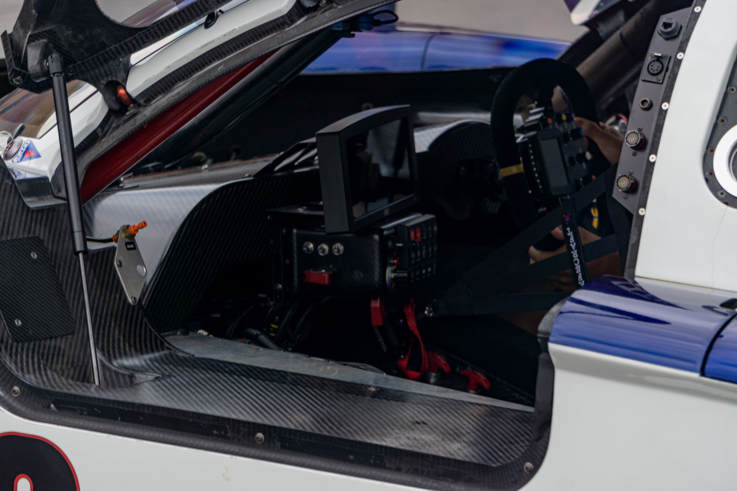 The carbon-fiber-heavy left-side interior view of Fall-Line Motorsports' white-red-and-blue Porsche Crawford Daytona Prototype