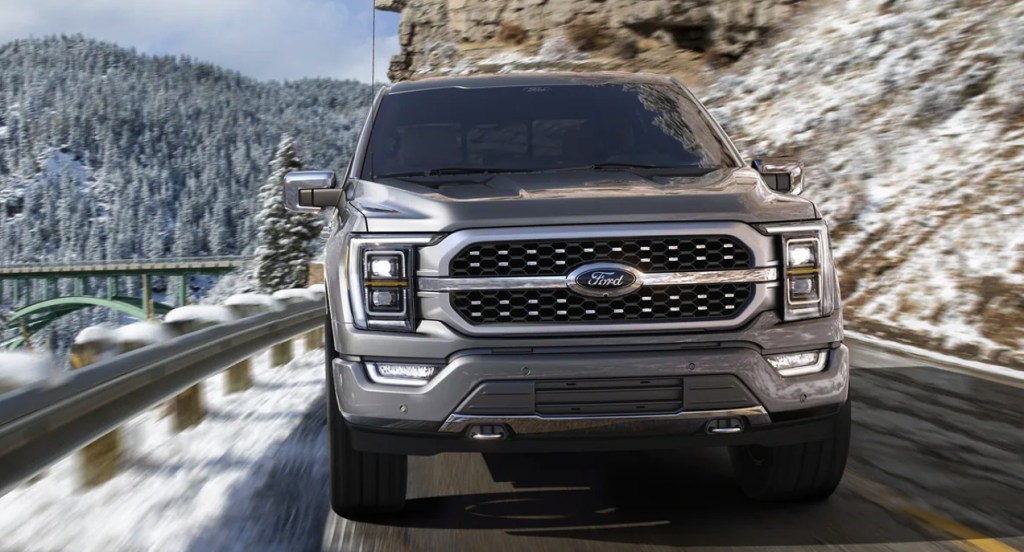 A gray Ford F-150 Lightning is driving on a snowy road.