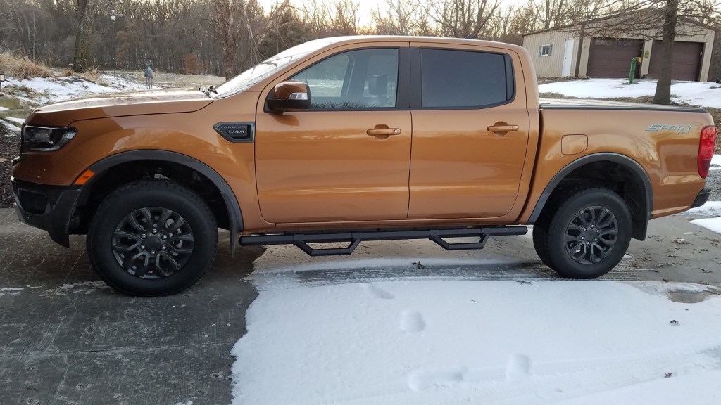 An orange Ford Ranger with nerf bars parked outside in snow