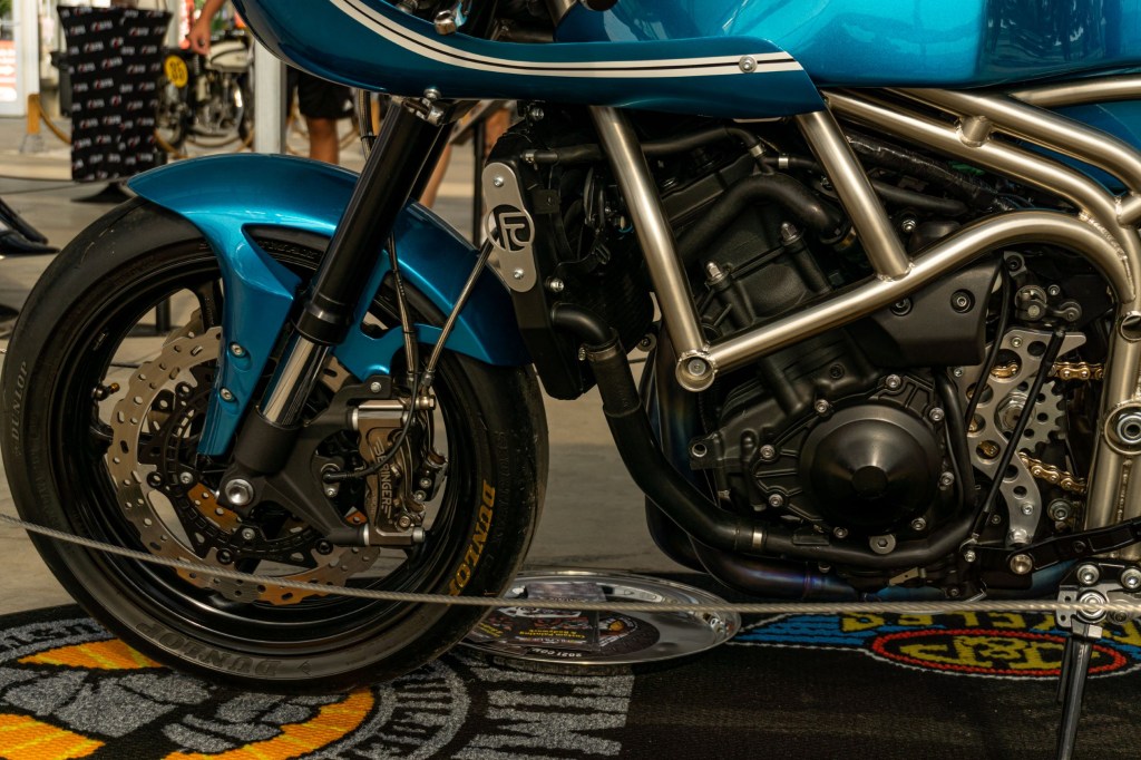 A closeup view of Robert Catanese's blue Framecrafters 2021 Yamaha YZF-R1 R1X's front brakes, engine, and chromoly-steel frame