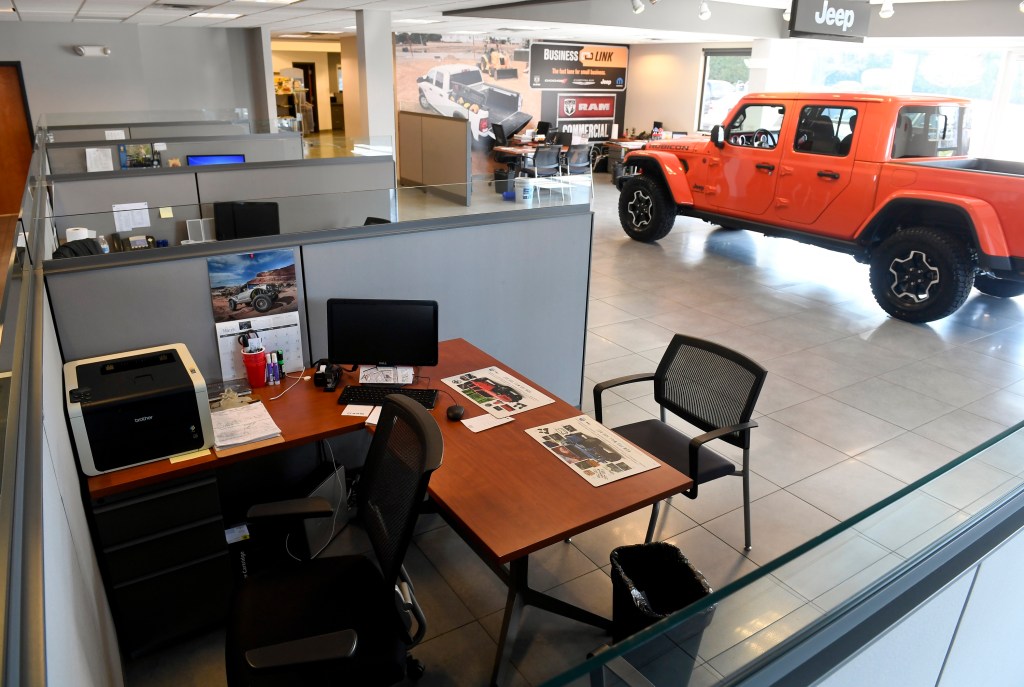 A Jeep dealership desk with a 2021 Jeep Gladiator truck in the background
