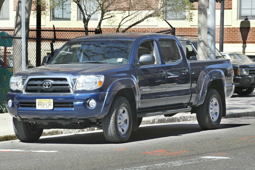 A blue Toyota Tacoma pickup truck is parked on a street. 